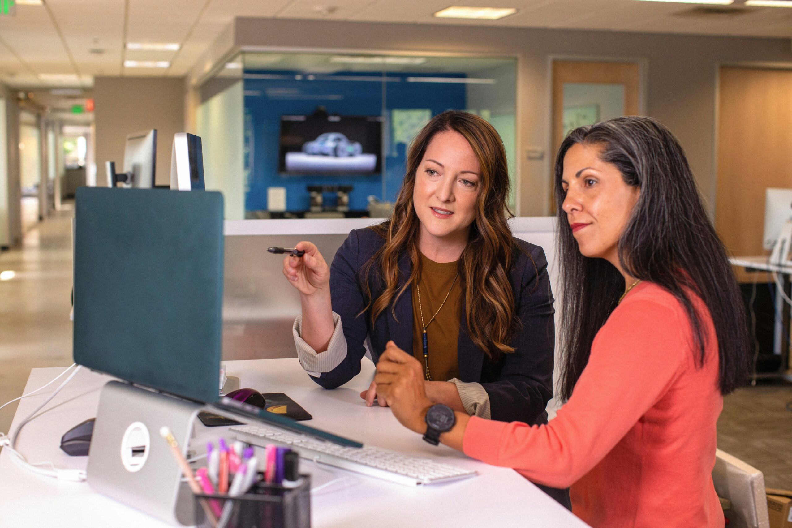two medical coder women talking to each other while looking at a screen