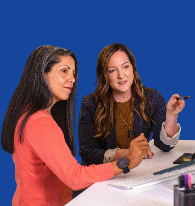 two medical coder women talking to each other while looking at a screen